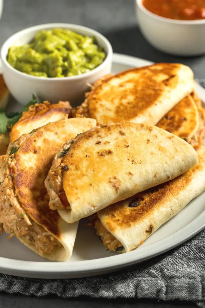 Plate of crispy quesadillas served with guacamole and salsa for a delicious Mexican meal.