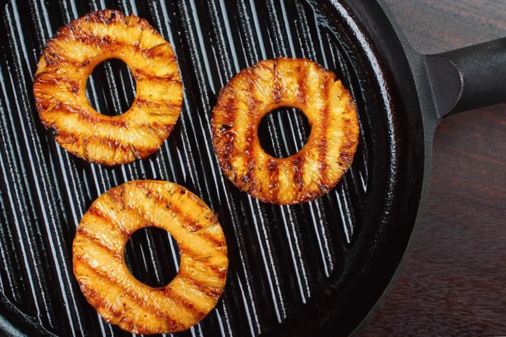 Grilled pineapple rings on a sizzling hot pan, perfect for a tropical treat or summer barbecue delight.