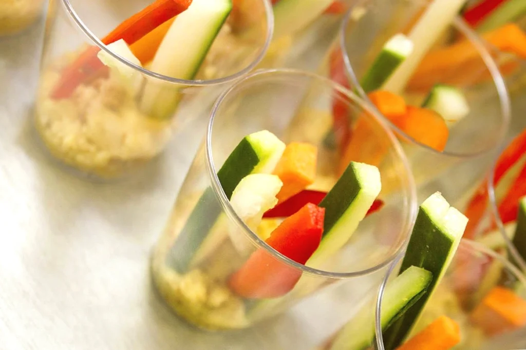 Colorful vegetable sticks in clear cups, ready for healthy snacking.