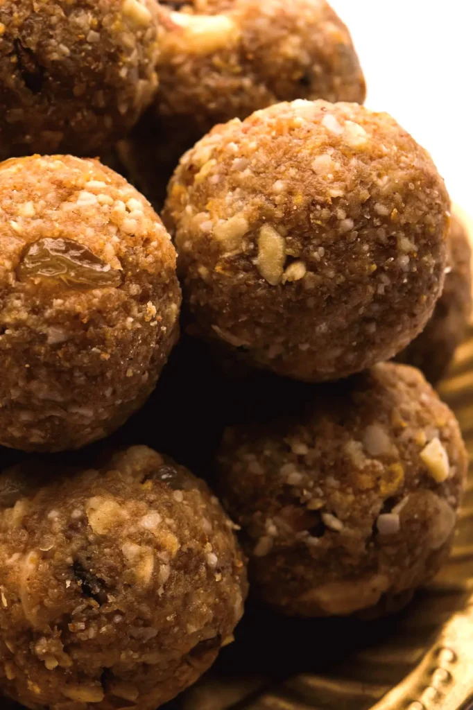 Close-up of traditional Indian sweet laddus on a golden plate, showcasing rich texture and ingredients.