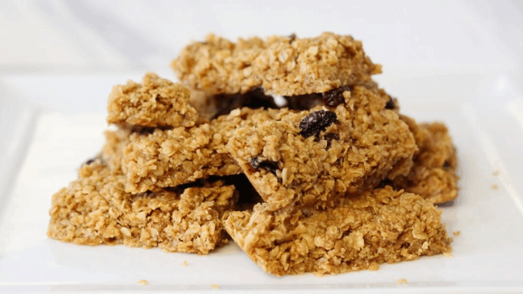 Stack of homemade oatmeal granola bars with raisins on a white plate.