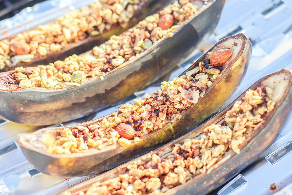 Grilled bananas filled with granola and nuts on a barbecue grill, a delicious outdoor dessert option.