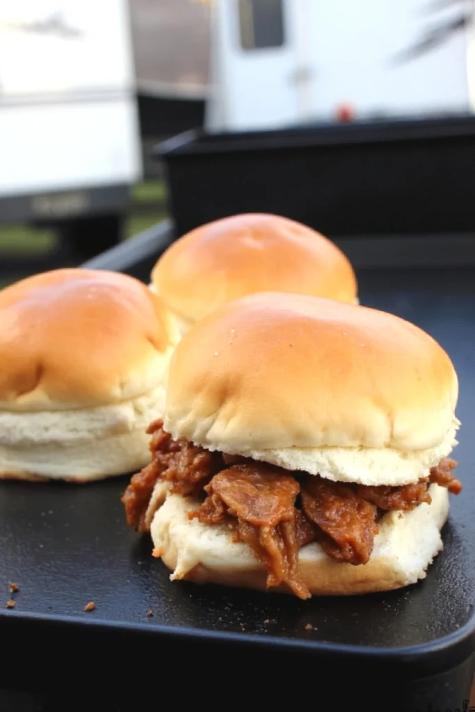 Pulled pork sliders on a grill, featuring soft buns and savory barbecue filling, perfect for a delicious meal.