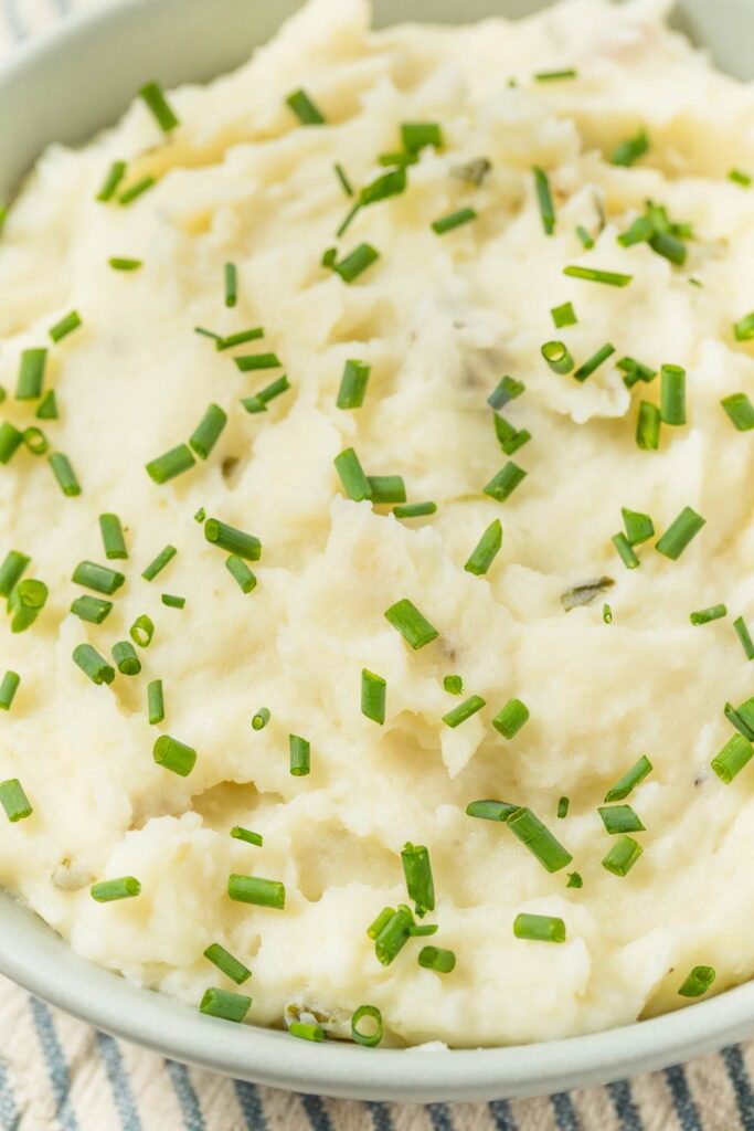 Creamy mashed potatoes garnished with fresh chopped chives in a bowl.