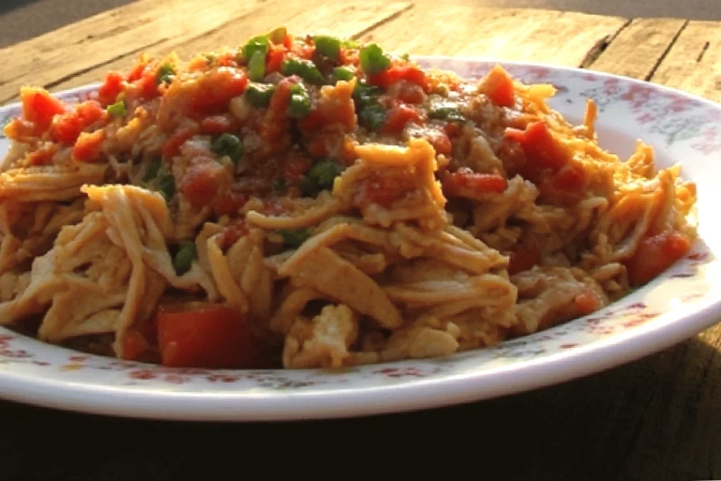 Shredded chicken breast with tomatoes and green peppers on a floral plate.