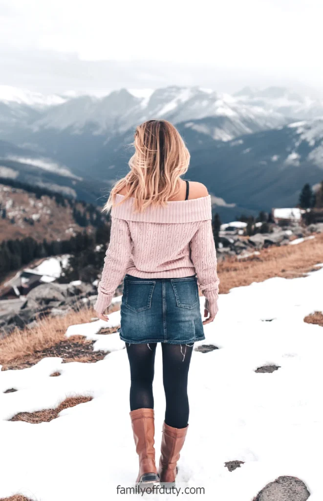 Woman in winter outfit walking through snowy mountain landscape.