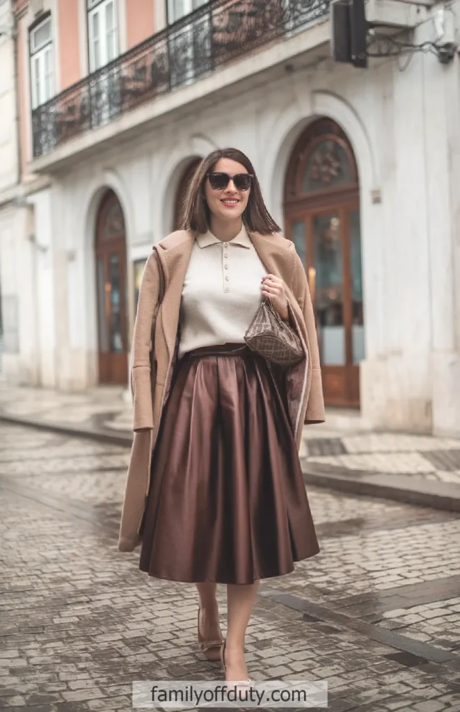 Woman in stylish outfit walking down a city street, wearing sunglasses and a long skirt.