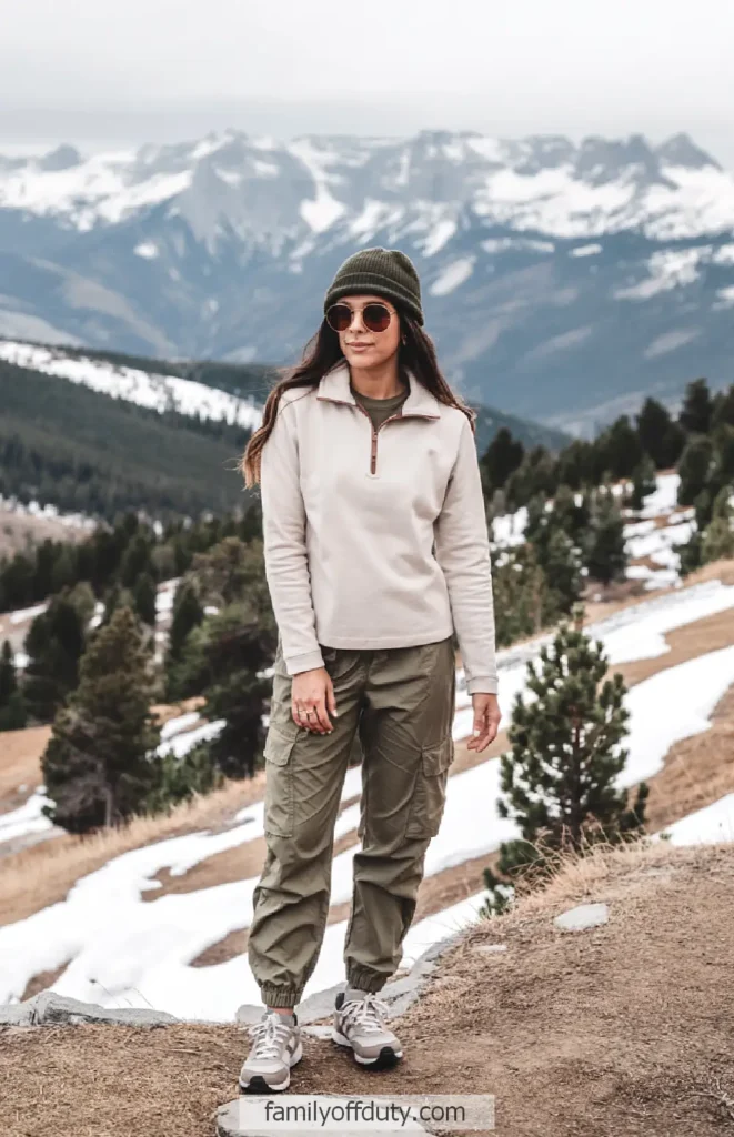 Woman in outdoor gear hiking in snowy mountain landscape.