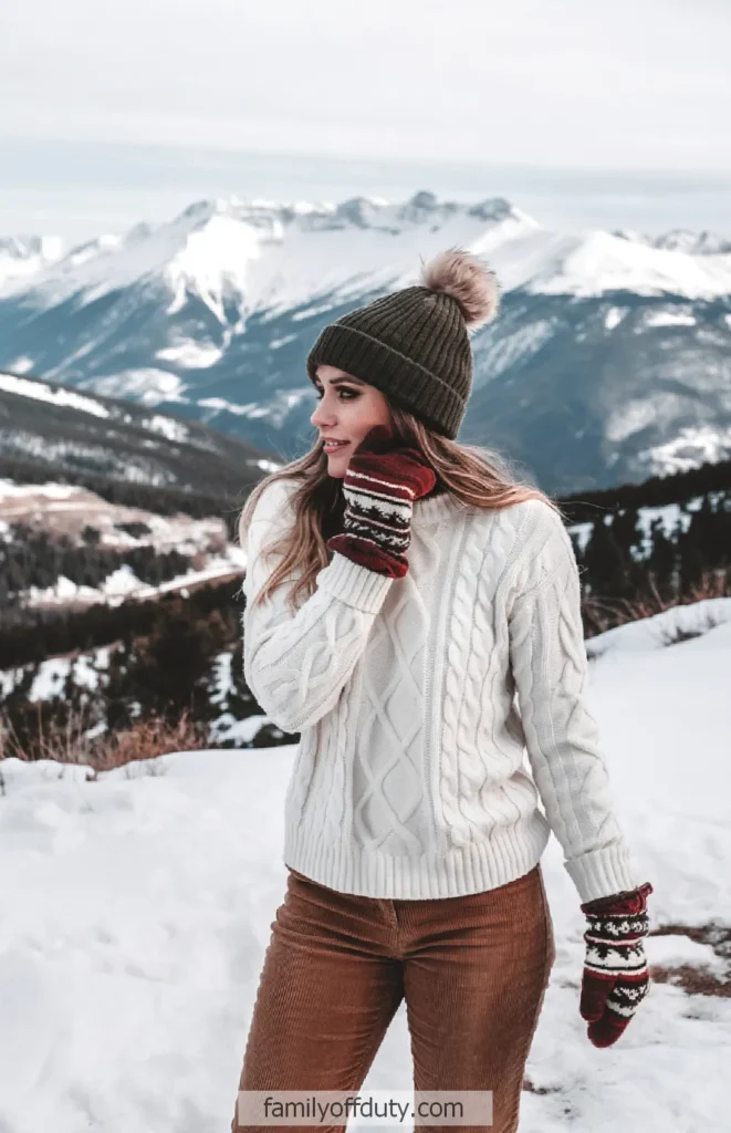 Woman in winter clothing enjoys snowy mountain view.