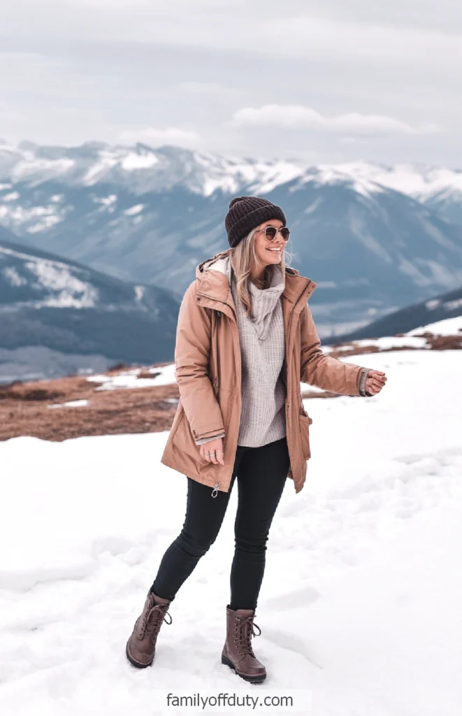Woman in winter attire enjoying snowy mountain landscape.