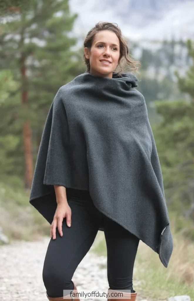 Smiling woman wearing a gray poncho in a forest setting.