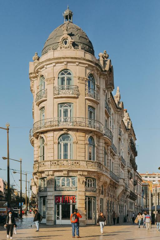 Historic European building with ornate details and dome, surrounded by people walking on a sunny day.