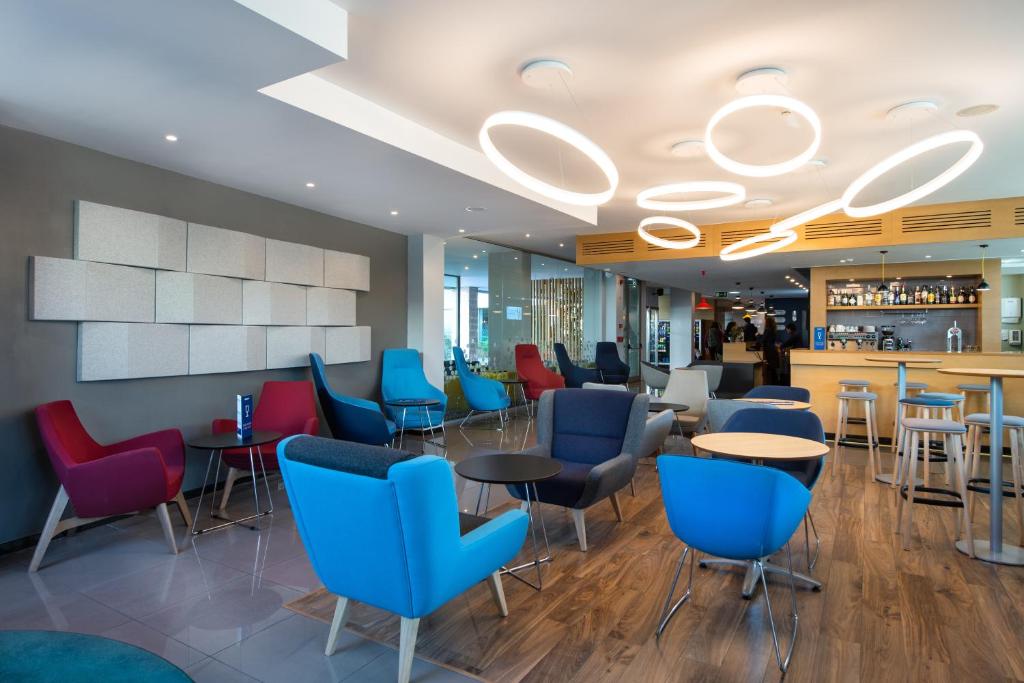 Modern hotel lobby with colorful chairs, circular lighting, and a stylish bar area, offering a welcoming atmosphere.