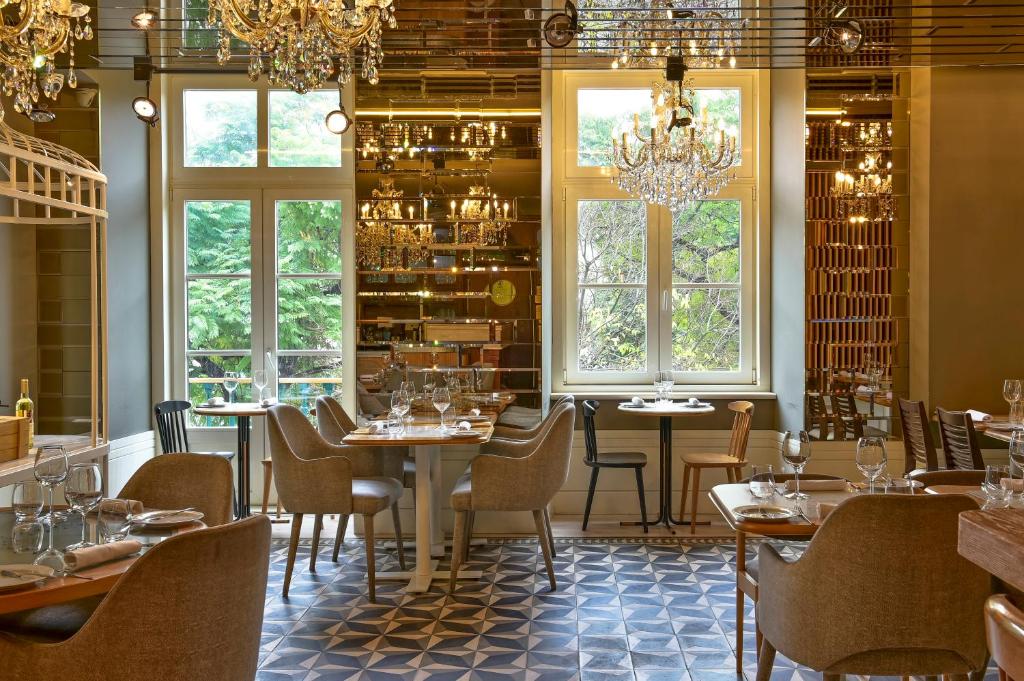 Elegant restaurant interior with chandeliers, stylish seating, and large windows overlooking lush greenery.