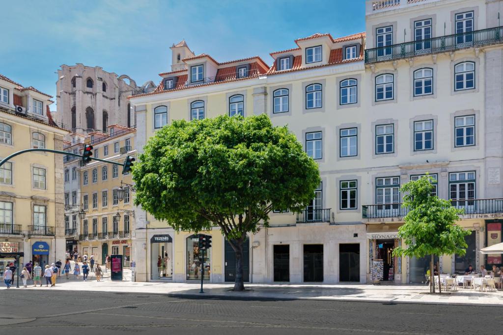 Historic Lisbon square with trees, traffic light, and old architecture under a clear blue sky.