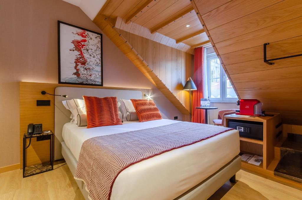 Cozy attic bedroom with modern decor, double bed, red accents, and a wooden ceiling. Bright window light.