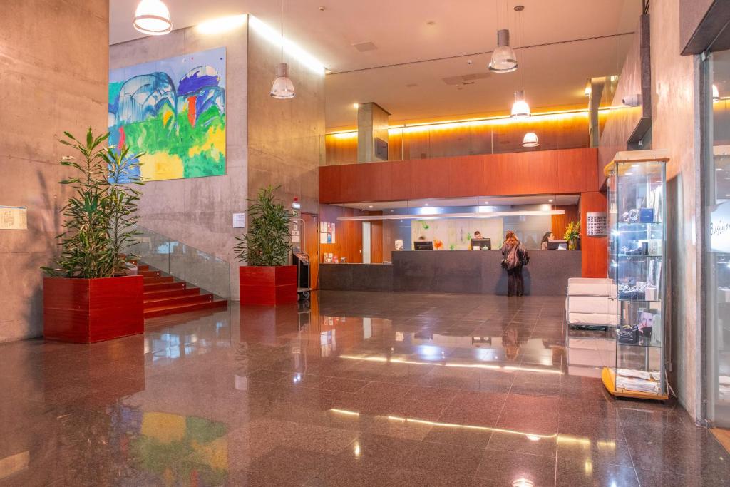 Modern hotel lobby with artwork, plants, and reception desk. Bright and inviting atmosphere.