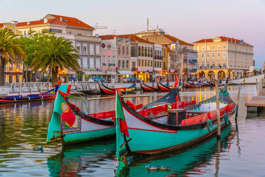 Colorful gondolas on a picturesque canal in Aveiro, Portugal, with charming historic buildings in the background.
