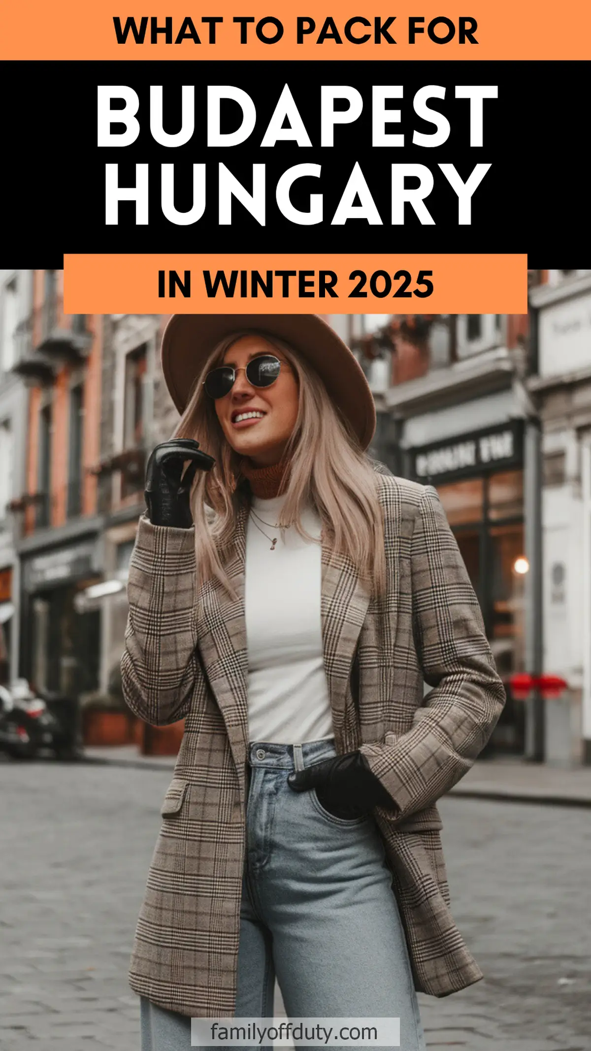 Stylish woman in winter outfit for Budapest 2025 trip, wearing hat, plaid jacket, and jeans on city street.