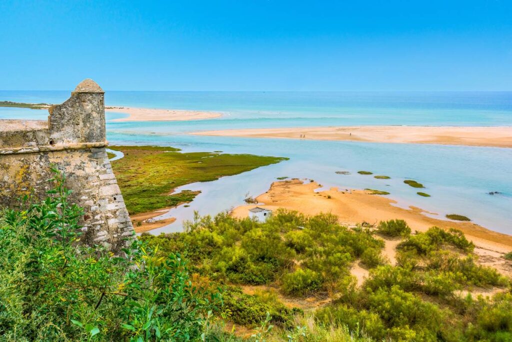 Historic Algarve fortress overlooking a scenic beach and turquoise sea under a clear blue sky.
