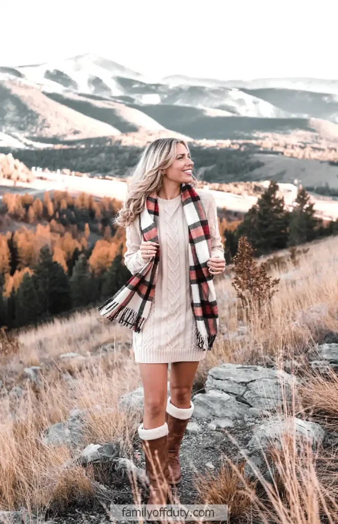 Woman in cozy winter outfit walking on scenic mountain trail in autumn.