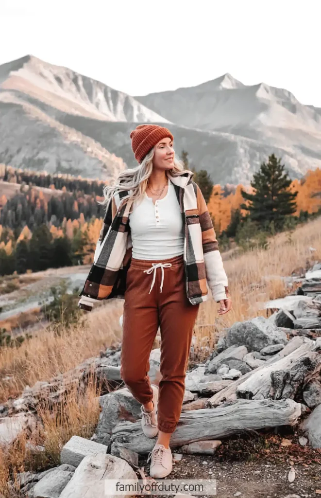 Woman enjoying a fall mountain hike in cozy casual wear with autumn foliage and scenic views.