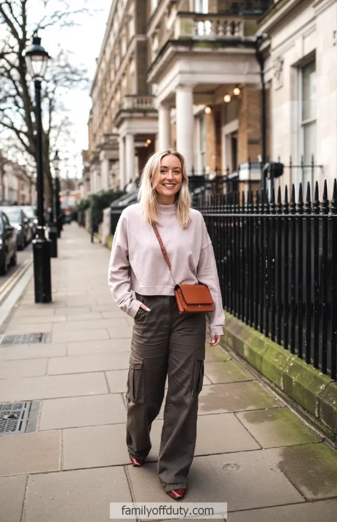 Woman walking confidently on a city sidewalk in a stylish outfit with a brown crossbody bag.