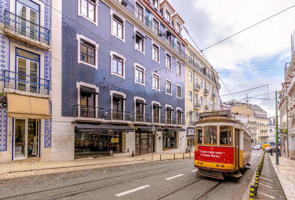 Historic yellow tram in Lisbon, Portugal, passing colorful tiled buildings on a charming city street.