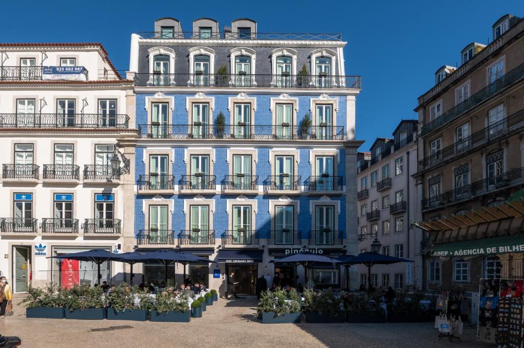 Blue and white building with outdoor café and balconies under clear sky in a European city street.