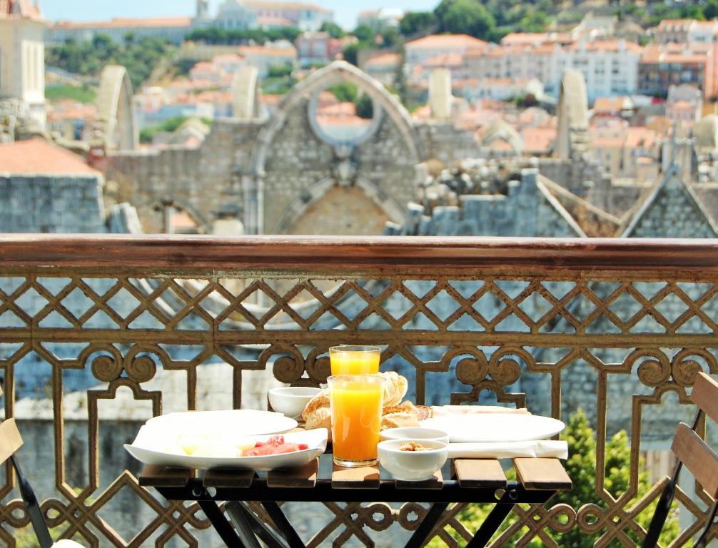 Breakfast with juice on a balcony overlooking scenic old town rooftops and ruins.