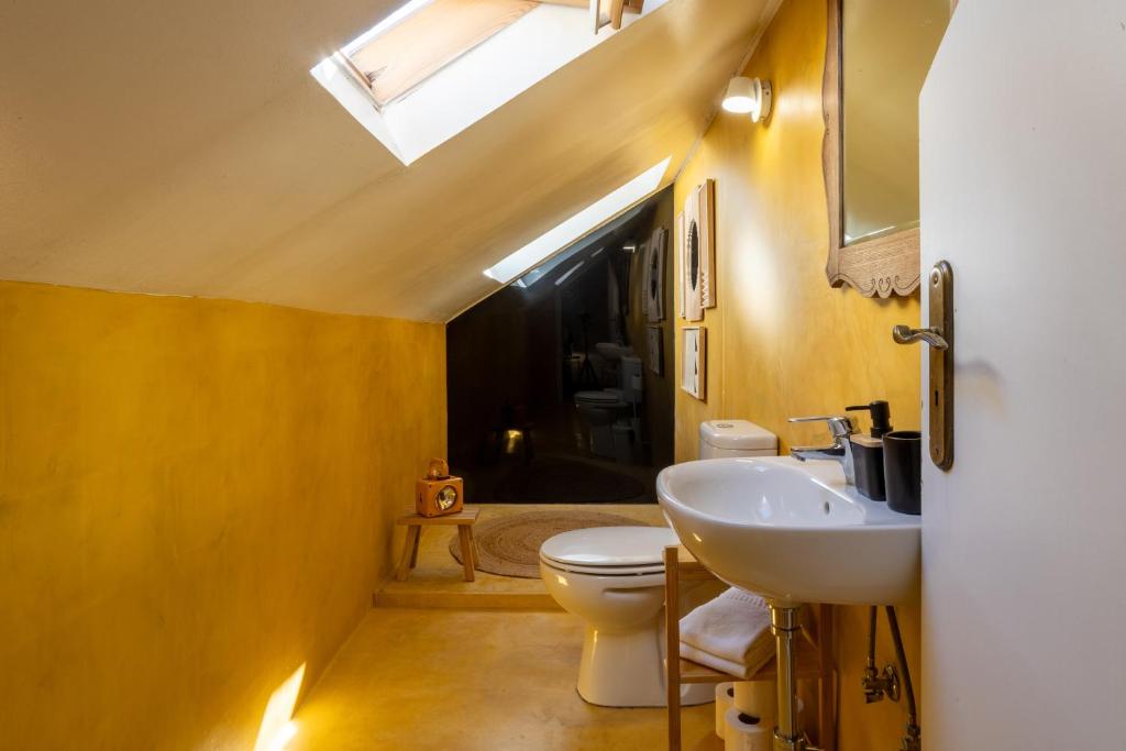 Cozy attic bathroom with a skylight, yellow walls, a sink, and a toilet, creating a warm and inviting atmosphere.