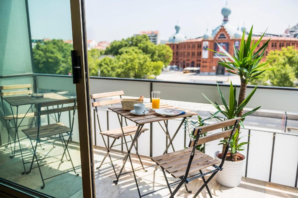 Sunny balcony with wooden table set, breakfast, and city view with historic building. Perfect urban relaxation spot.