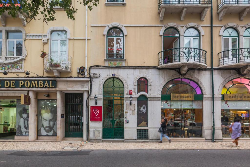 Street view of Lisbon building with shops and people walking by on a cloudy day.