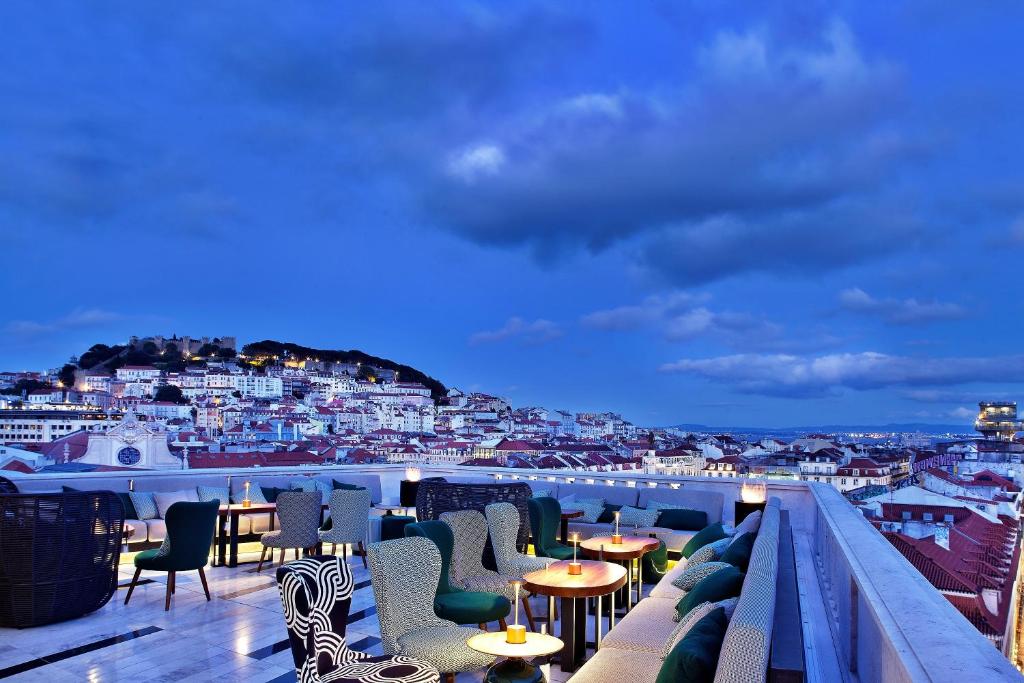 Rooftop bar overlooking Lisbon cityscape at twilight with seating and city views under a deep blue sky.