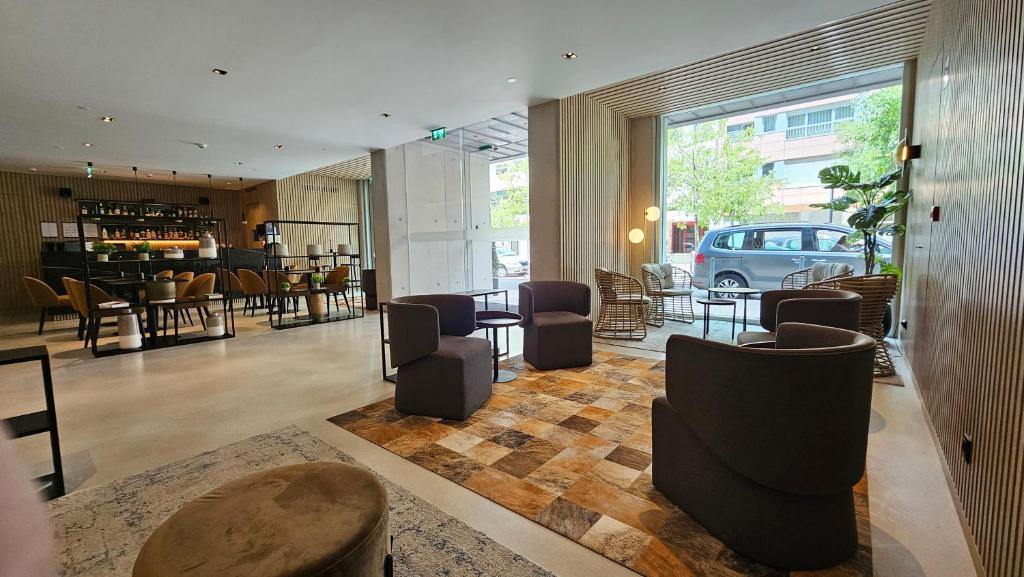 Modern hotel lobby with stylish seating, large window, and adjacent bar area. Inviting space with neutral tones.
