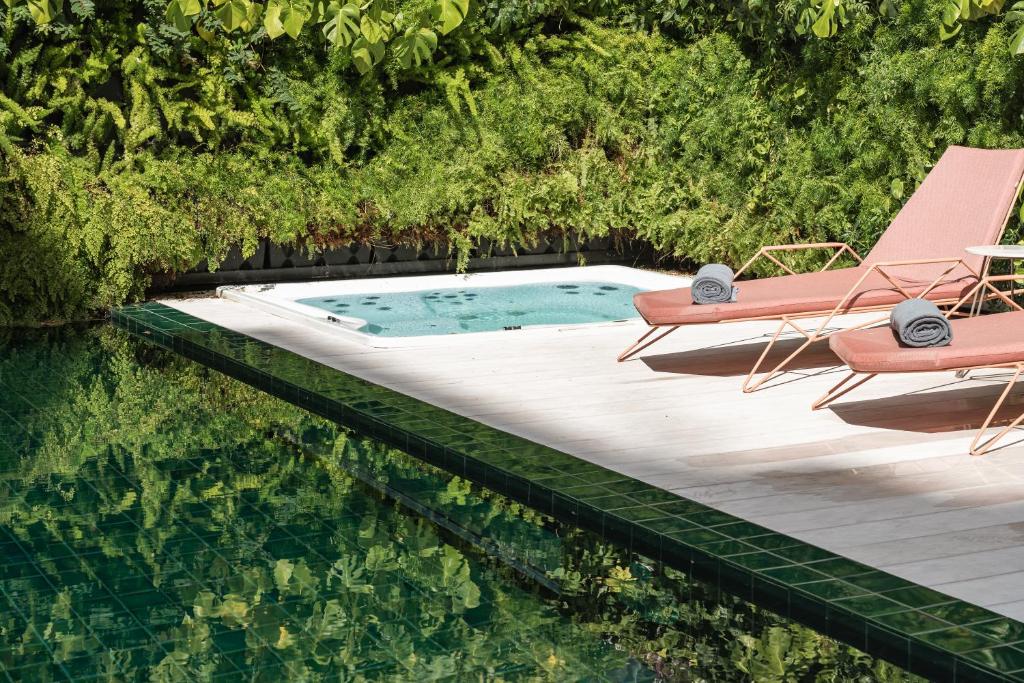 Luxurious poolside with green foliage, sun loungers, and a spa bath, perfect for relaxation and leisure.