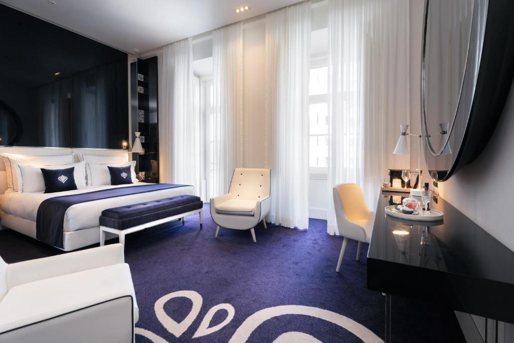 Elegant hotel room with modern decor, king-size bed, and soft lighting, featuring a purple carpet and white chairs.