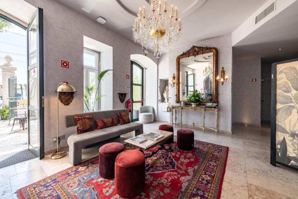 Elegant hotel lounge with chandelier, vintage rug, plush seating, and large mirrors creating an inviting, luxurious ambiance.