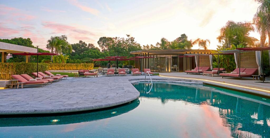 Luxury resort pool at sunset with lounge chairs, umbrellas, and tropical landscaping enhancing the serene ambiance.