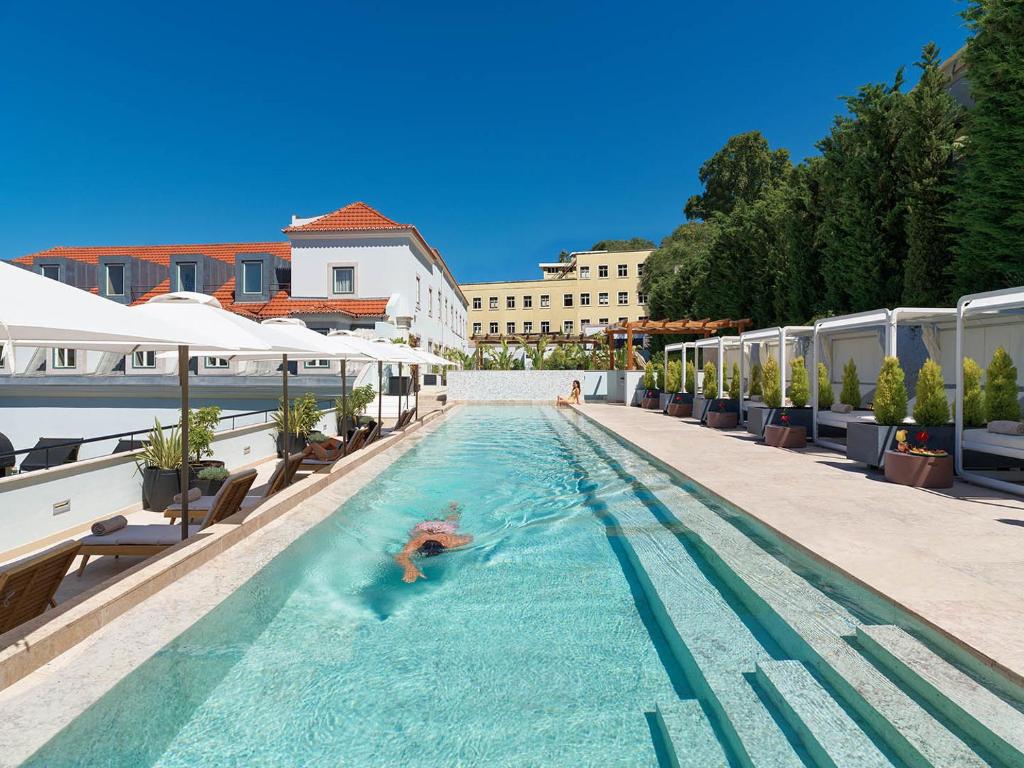 Outdoor pool at a luxury resort, with lounge chairs and cabanas under blue skies, inviting relaxation and leisure.