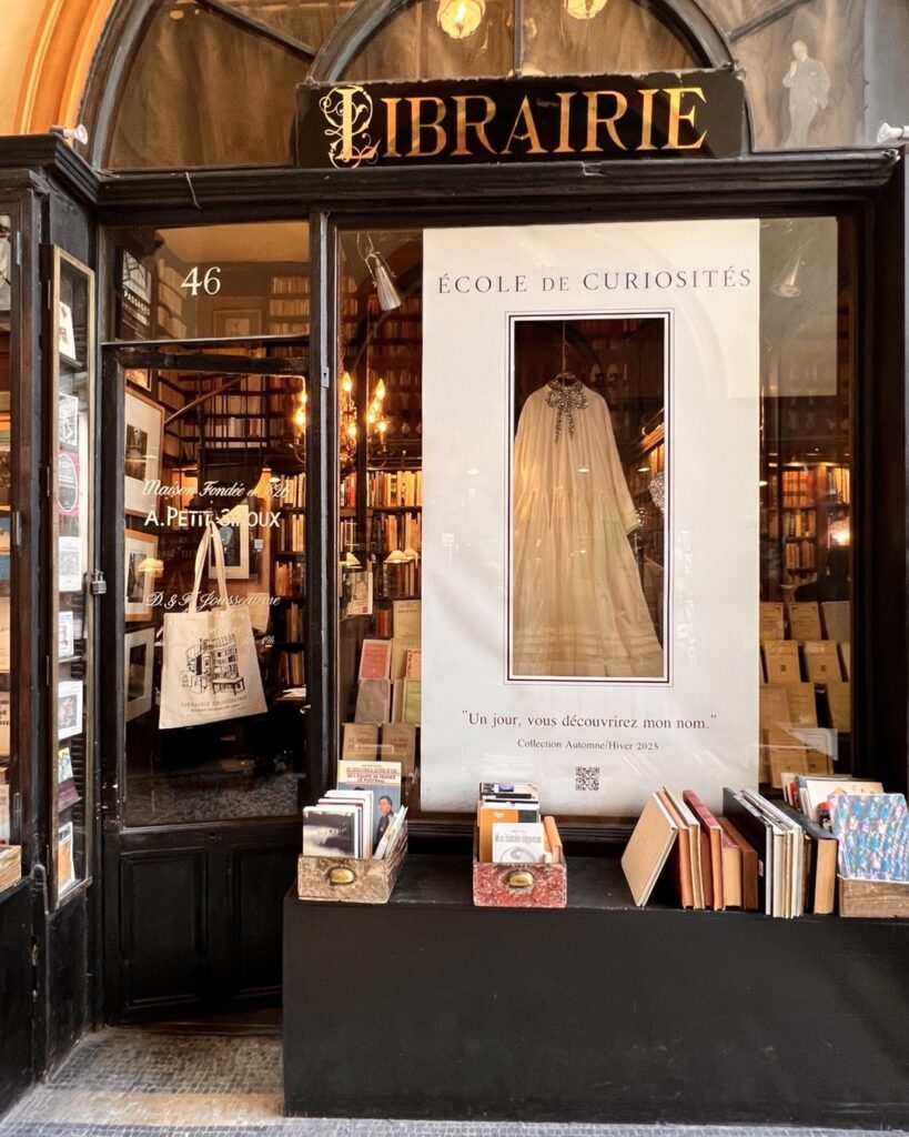 Cozy Parisian bookstore with a stylish window display featuring vintage books and a classic dress design.