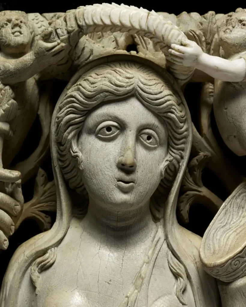 Ancient ivory relief depicting a crowned figure, with intricate details and cherubs, showcasing classical artistry.