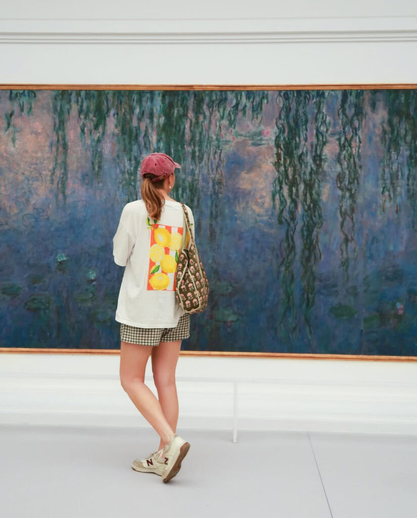 Person in casual attire admiring large abstract painting in a gallery.