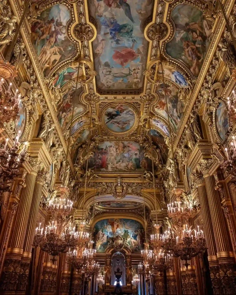Lavishly decorated ceiling of an ornate hall with intricate frescoes and chandeliers.