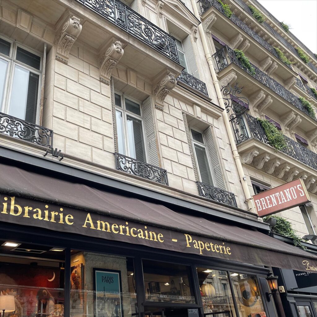 Front view of Parisian bookstore Librairie Americaine, with elegant facade and decorative balconies.