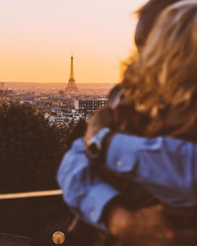 Couple embracing with Eiffel Tower view at sunset in Paris, capturing romantic city skyline.