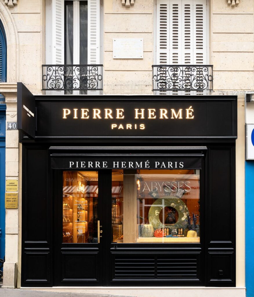 Front view of Pierre Hermé Paris bakery with elegant black and gold exterior.