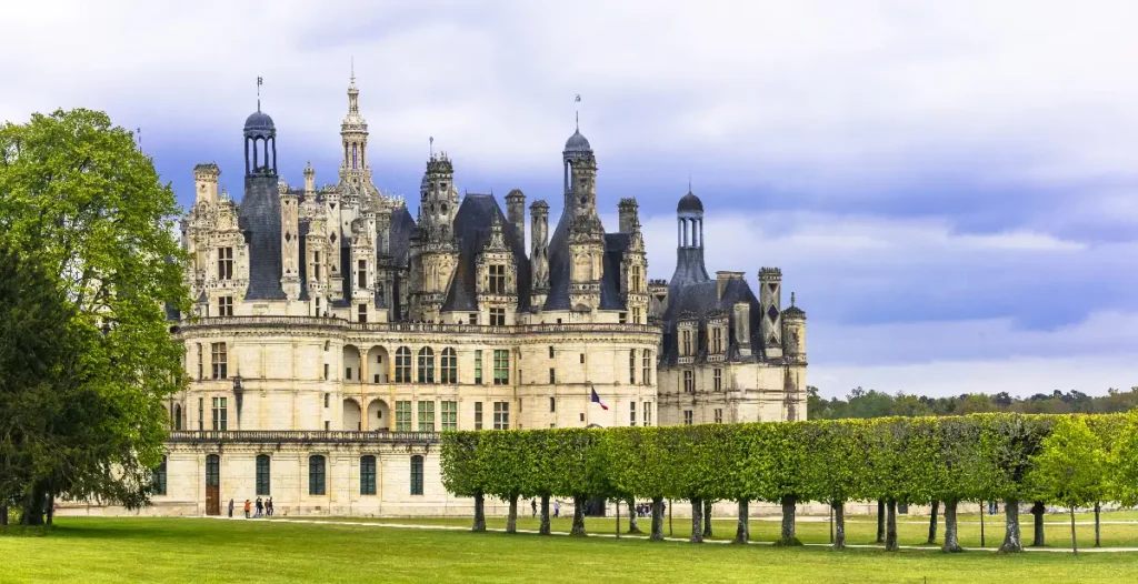 Château de Chambord, a stunning French castle, surrounded by lush greenery and dramatic clouds. Historic architectural beauty.