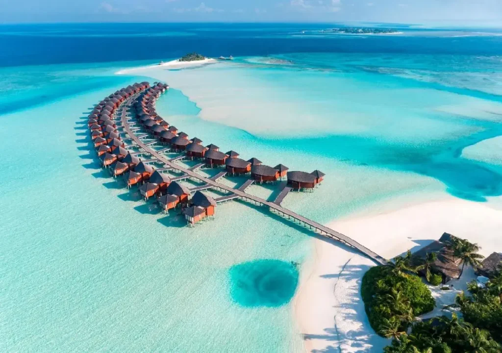 Aerial view of luxury overwater bungalows in turquoise waters, surrounded by pristine beaches and lush greenery.