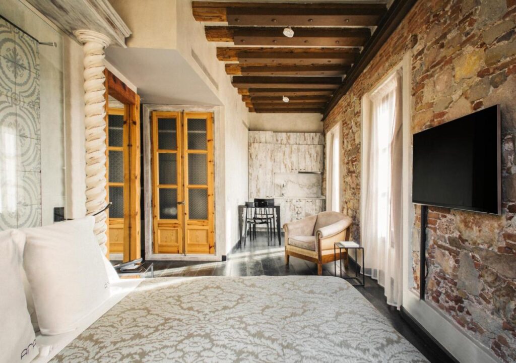 Stylish bedroom with exposed brick walls, wooden beams, and modern furnishings, perfect for a cozy getaway.